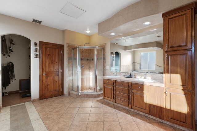 bathroom featuring a sink, visible vents, a stall shower, and double vanity