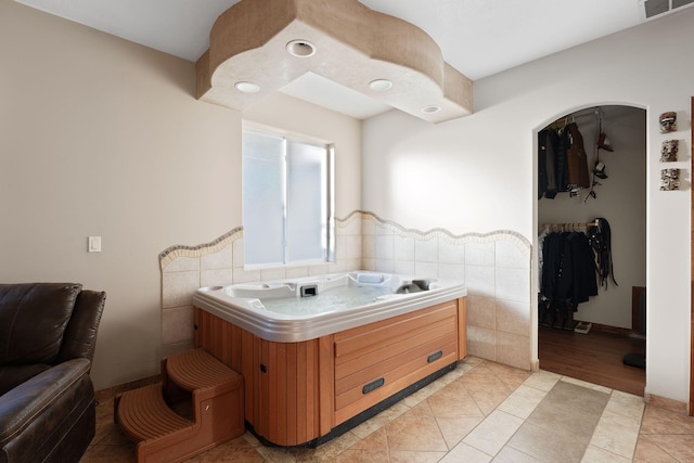 bathroom featuring tile patterned flooring, visible vents, a spacious closet, and tile walls