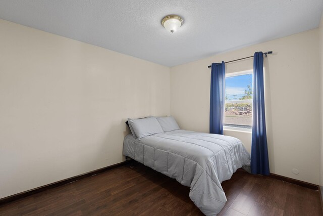 bedroom featuring wood finished floors, baseboards, and a textured ceiling