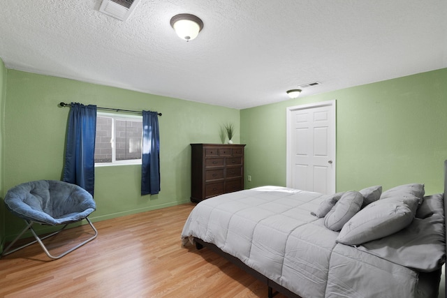 bedroom with a textured ceiling and light hardwood / wood-style floors