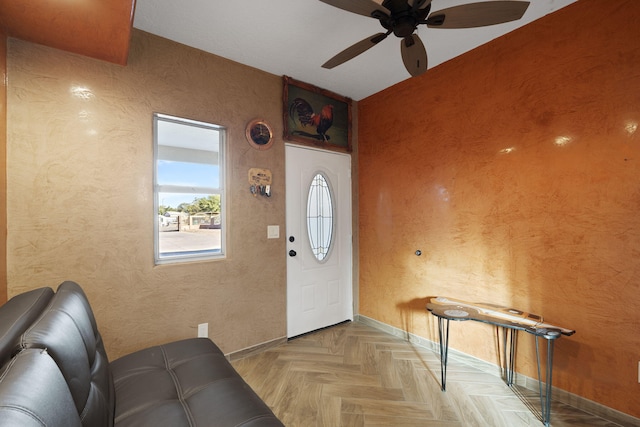 foyer entrance with baseboards, ceiling fan, and a textured wall