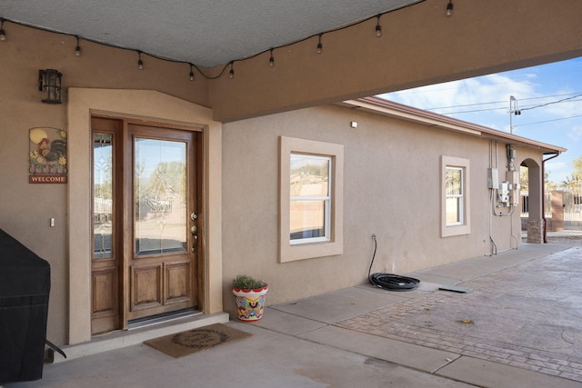 property entrance featuring stucco siding and a patio
