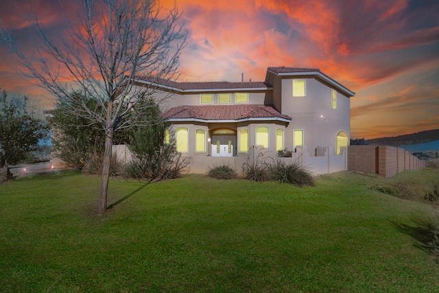 back house at dusk with a lawn