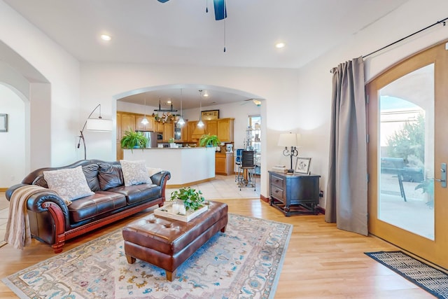 living room featuring light hardwood / wood-style flooring and ceiling fan with notable chandelier