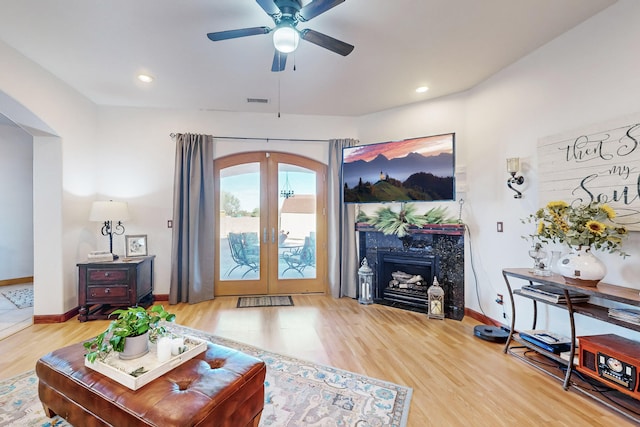 living room with french doors, hardwood / wood-style floors, a high end fireplace, and ceiling fan