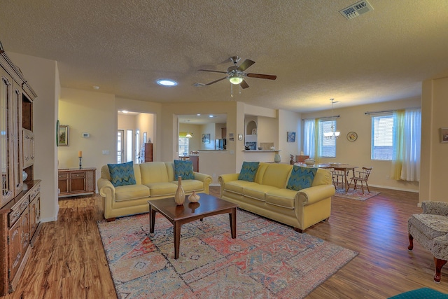 living room with a textured ceiling, ceiling fan, and wood-type flooring