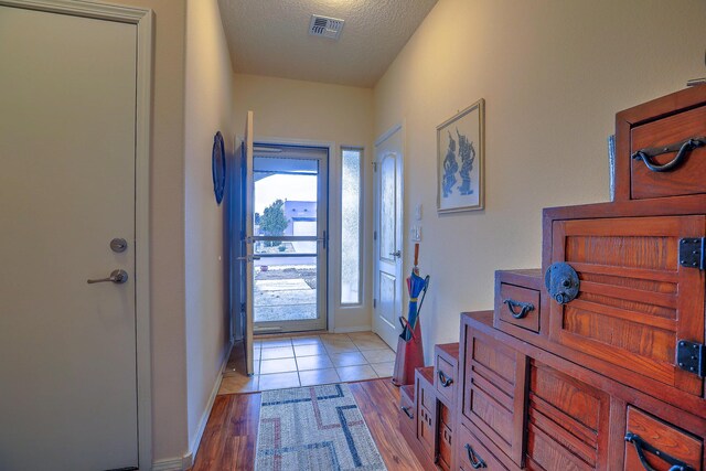 entryway featuring a textured ceiling and light hardwood / wood-style floors