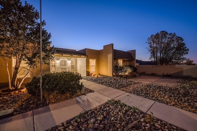 adobe home featuring a tile roof and fence