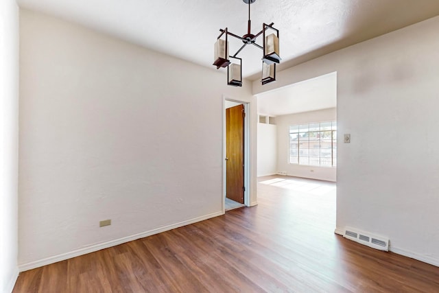 unfurnished dining area featuring wood-type flooring and a notable chandelier