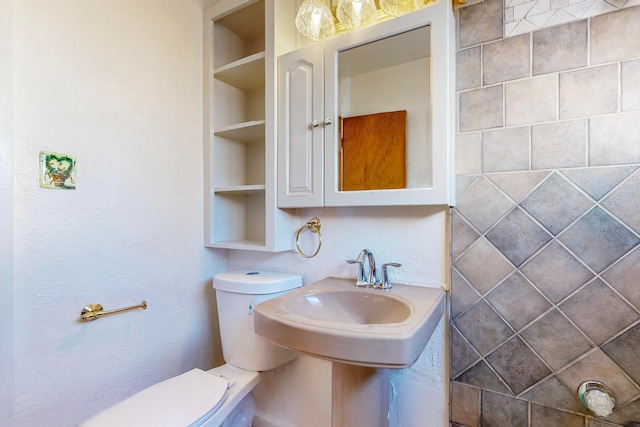 bathroom with toilet, built in features, and sink