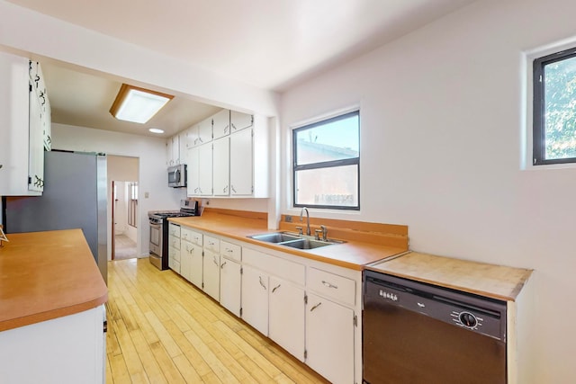 kitchen featuring stainless steel appliances, white cabinetry, a wealth of natural light, and sink