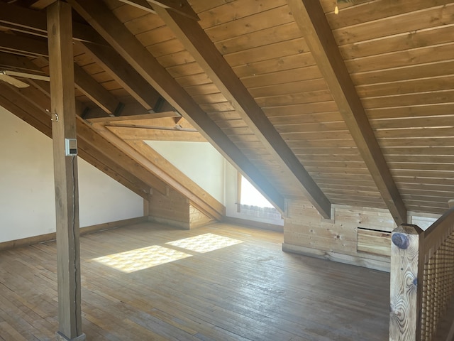 bonus room featuring lofted ceiling with beams, hardwood / wood-style flooring, and baseboards