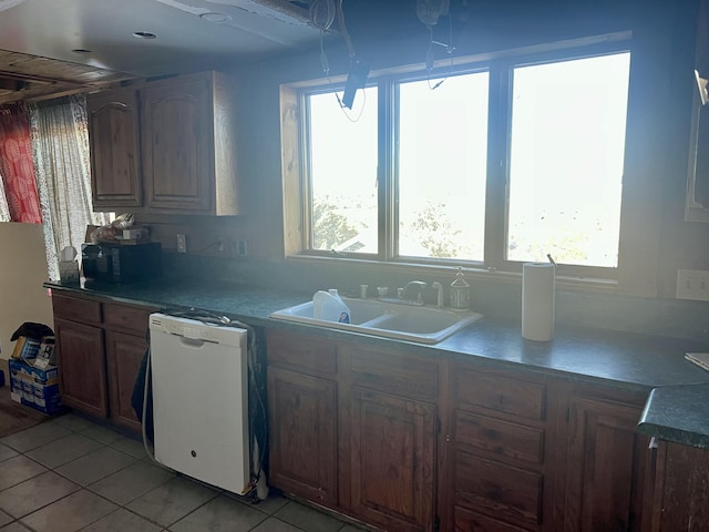 kitchen featuring a healthy amount of sunlight, sink, white dishwasher, and light tile patterned floors