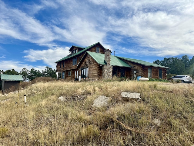 exterior space featuring a chimney, metal roof, and log exterior