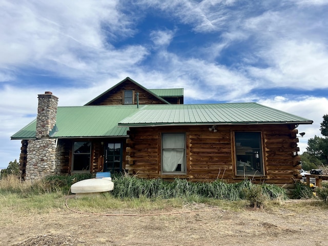 exterior space featuring metal roof, a chimney, and log siding