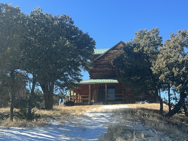 view of property exterior with log exterior, metal roof, and a porch