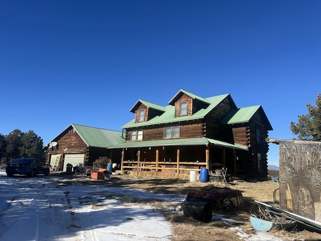 log cabin featuring a porch, metal roof, and log exterior