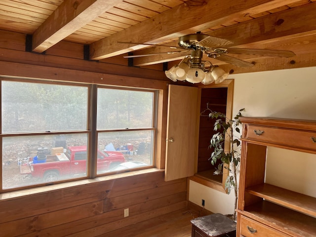 interior space with wooden walls, a ceiling fan, wood ceiling, beamed ceiling, and wood finished floors