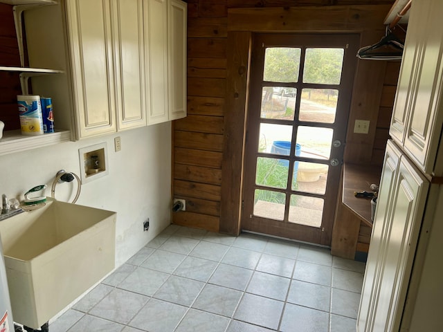 clothes washing area featuring cabinets, wooden walls, hookup for a washing machine, and sink