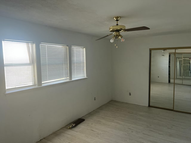 unfurnished bedroom with light wood-type flooring, ceiling fan, and a closet