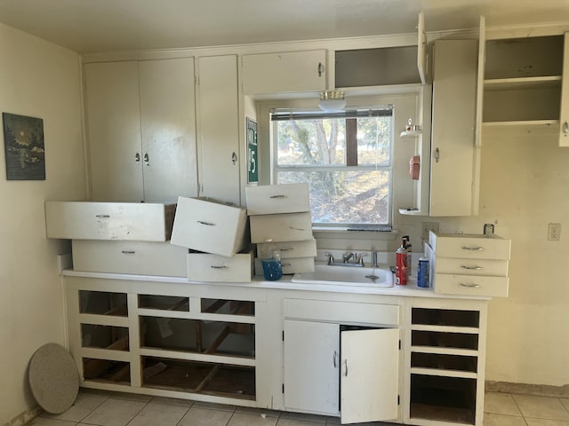 kitchen featuring open shelves, light tile patterned floors, light countertops, and a sink