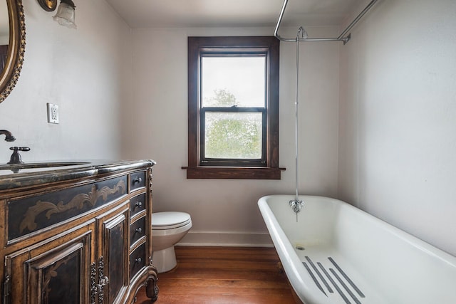 bathroom featuring toilet, vanity, hardwood / wood-style flooring, and a bathing tub