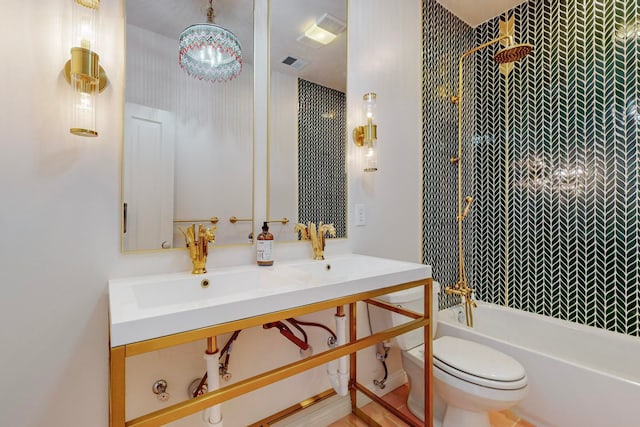 full bathroom featuring vanity, tiled shower / bath combo, and toilet