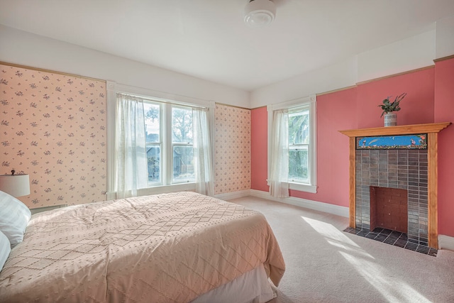 bedroom with multiple windows, a tile fireplace, and carpet