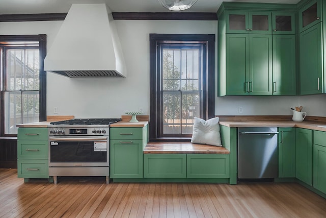 kitchen featuring light wood-type flooring, stainless steel appliances, a healthy amount of sunlight, and premium range hood