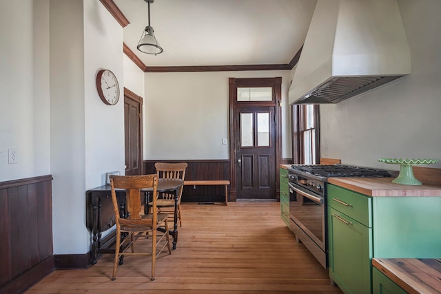 kitchen with wooden counters, light hardwood / wood-style floors, custom range hood, stainless steel range, and decorative light fixtures