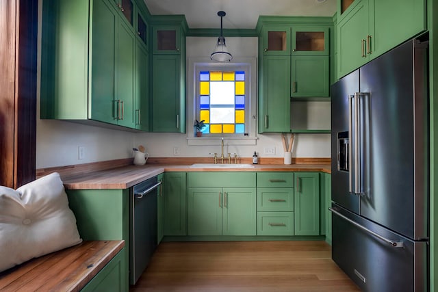 kitchen with wooden counters, stainless steel appliances, light hardwood / wood-style floors, green cabinets, and pendant lighting