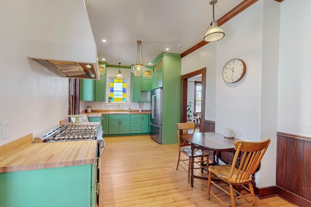 kitchen featuring stainless steel appliances, butcher block counters, light hardwood / wood-style floors, green cabinets, and custom exhaust hood