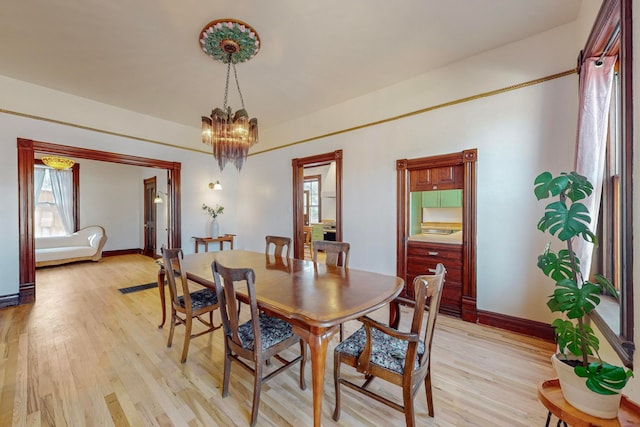 dining room with light wood-type flooring and a notable chandelier