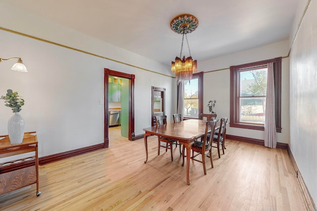 dining space with light hardwood / wood-style flooring and a notable chandelier