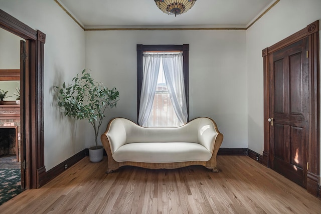 sitting room with ornamental molding and light hardwood / wood-style floors