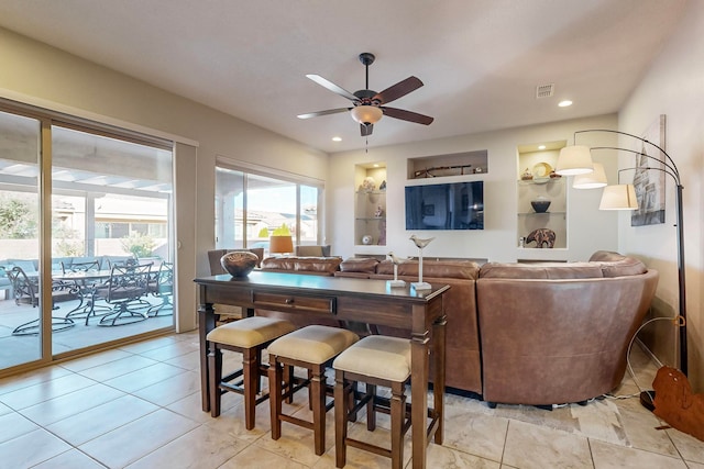 tiled living room featuring built in features and ceiling fan