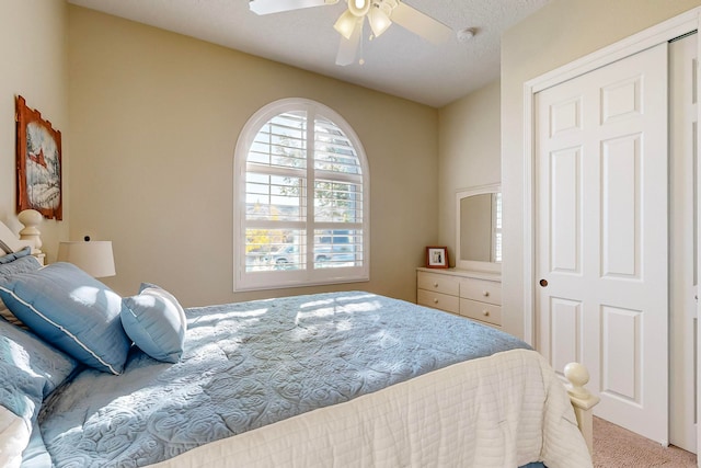 bedroom featuring a textured ceiling, light colored carpet, and ceiling fan