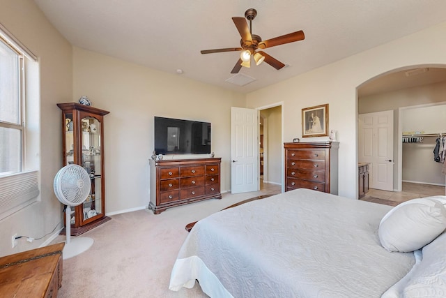 carpeted bedroom featuring a closet, ceiling fan, and a walk in closet