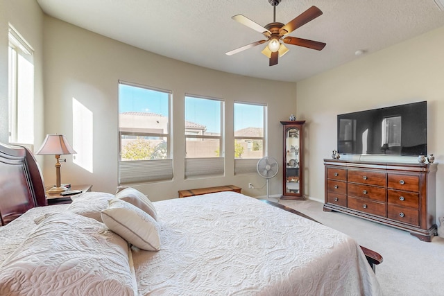 bedroom with ceiling fan, a textured ceiling, and light colored carpet