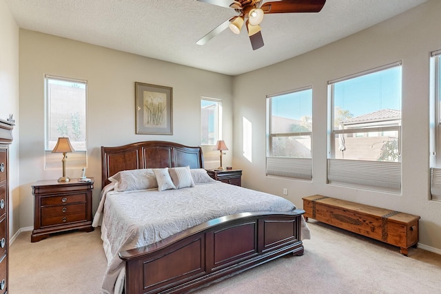 bedroom with a textured ceiling, light colored carpet, and ceiling fan