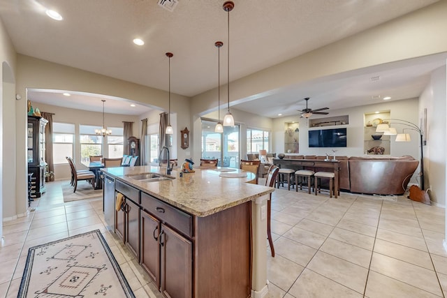 kitchen featuring decorative light fixtures, sink, plenty of natural light, and an island with sink