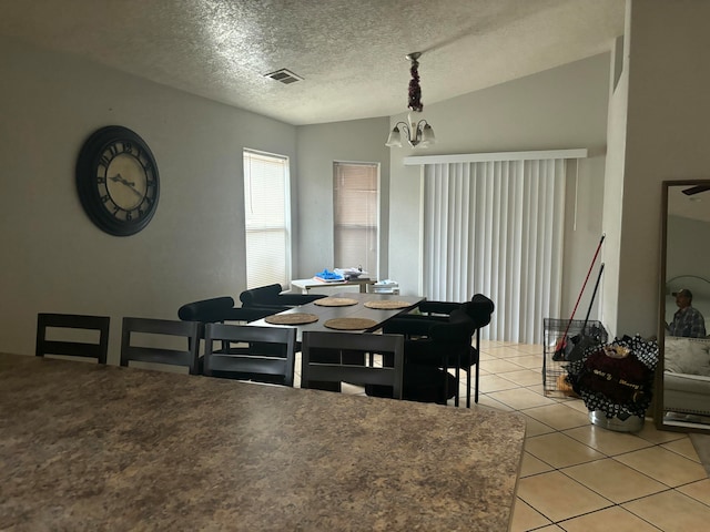 dining room with lofted ceiling, a textured ceiling, a notable chandelier, and light tile patterned floors