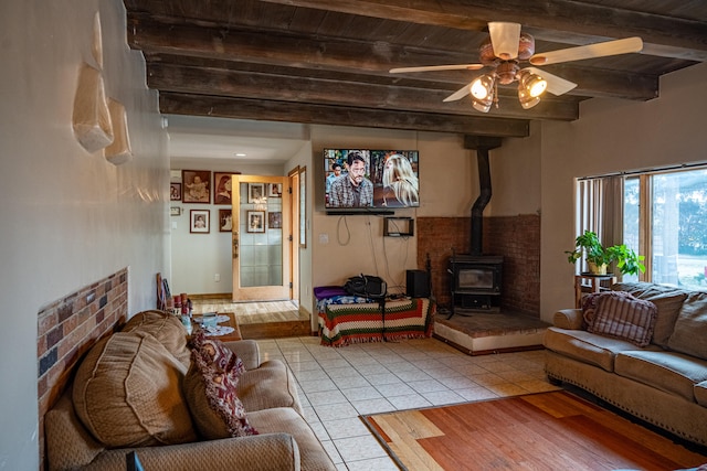 living room featuring wooden ceiling, ceiling fan, beam ceiling, a wood stove, and light hardwood / wood-style flooring