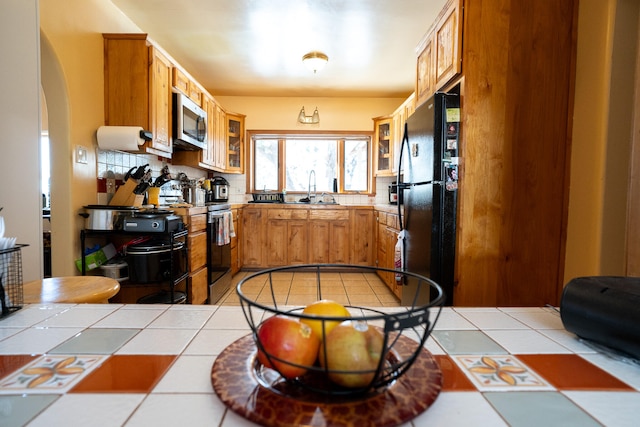 kitchen with tile countertops, sink, decorative backsplash, and stainless steel appliances