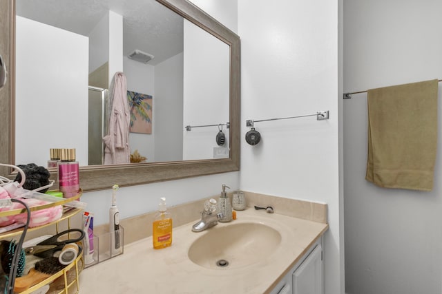 bathroom featuring walk in shower, vanity, and a textured ceiling