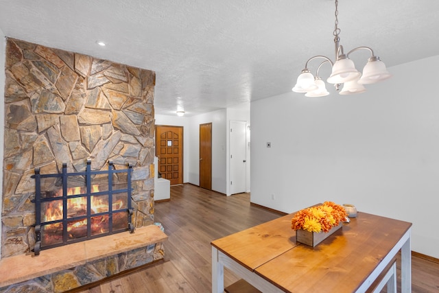 dining room with wood-type flooring, a textured ceiling, and a notable chandelier