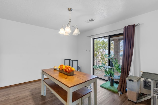 dining area featuring wood-type flooring, a textured ceiling, and an inviting chandelier