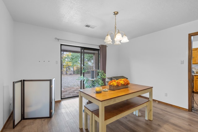 dining area with a chandelier, a textured ceiling, and light wood-type flooring