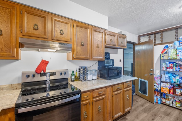 kitchen featuring a textured ceiling, light hardwood / wood-style flooring, and electric range