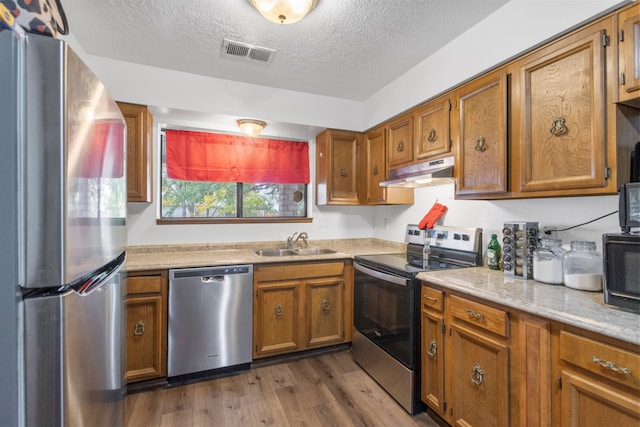 kitchen featuring appliances with stainless steel finishes, sink, dark hardwood / wood-style floors, and a textured ceiling